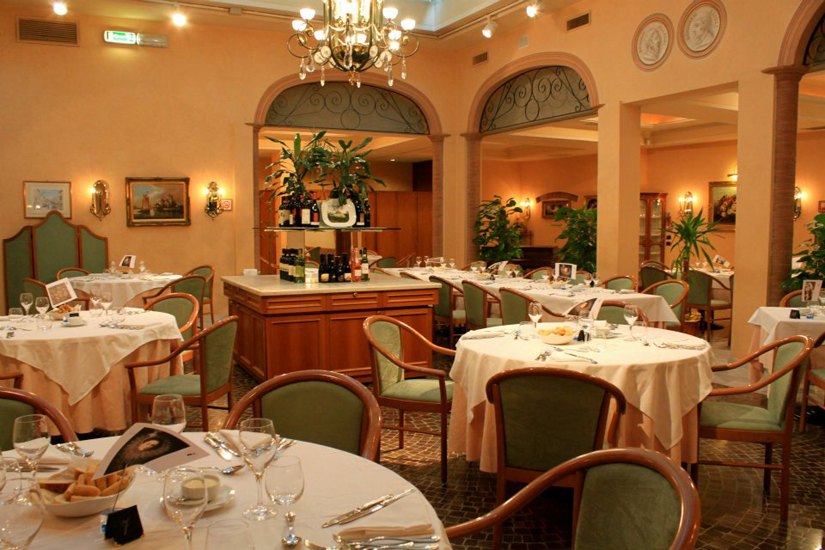 La sala del ristorante con tavoli rotondi e finestre ad arco